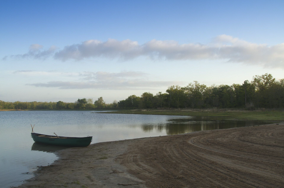 a boat sits on shore on a lake at a nature conservancy in Texas