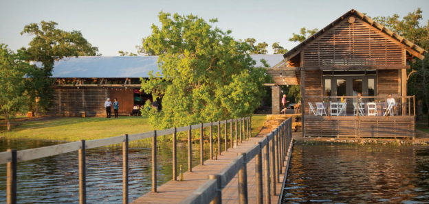 A wooden dock stretches over a lake from the boathouse